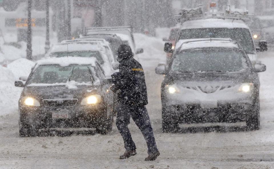 A pedestrian crosses the street in front of vehicles during a snowstorm, Sunday, Feb. 12, 2017, in Waltham, Mass. (AP Photo/Steven Senne)