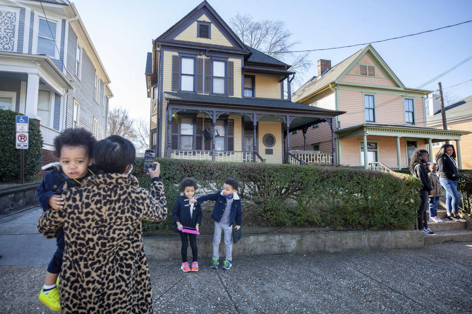 Alexis Upshaw, left, holding 2-year-old Ari Upshaw, takes a photo as Ty Upshaw, 7, right, adjusts the mask of his sister, Mila Upshaw, 5, in front of the birthplace of Dr. Martin Luther King, Jr. on Monday, Jan. 18, 2021, the Martin Luther King Jr. holiday, in Atlanta. (AP Photo/Branden Camp)