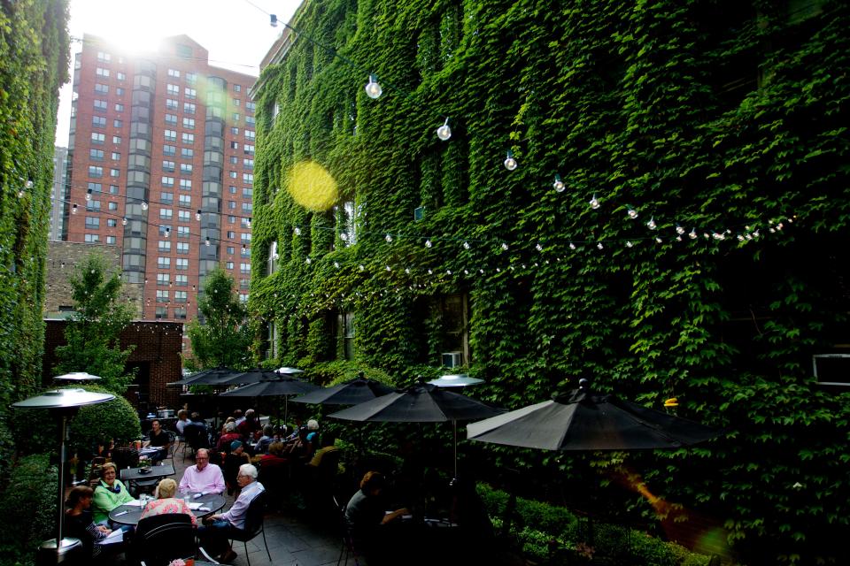 The courtyard at Cafe at the Plaza is a tranquil, tucked-away space with cafe tables and lush ivy lining the exterior brick walls.