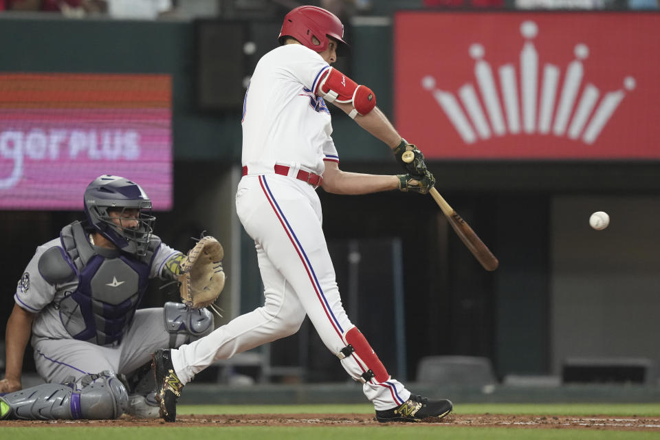 Texas Rangers' Nathaniel Lowe, right, hits a single in front of Colorado Rockies catcher Elias Diaz scoring Rangers' Marcus Semien during the first inning of a baseball game in Arlington, Texas, Saturday, May 20, 2023. (AP Photo/LM Otero)