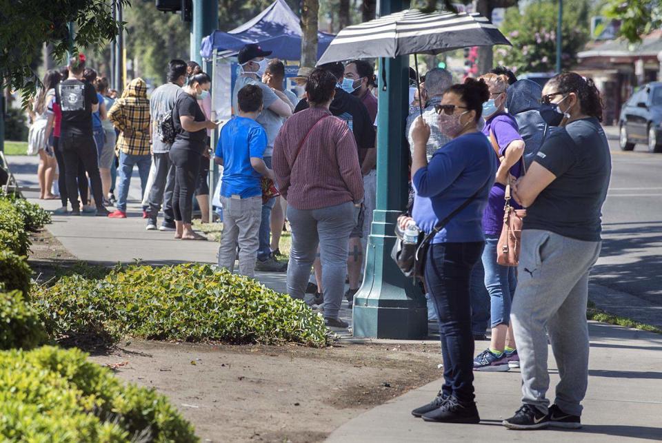 Hundreds of people wait at the back of the line for COVID-19 testing near Lodi, California's Rancho San Miguel Market on July 3.