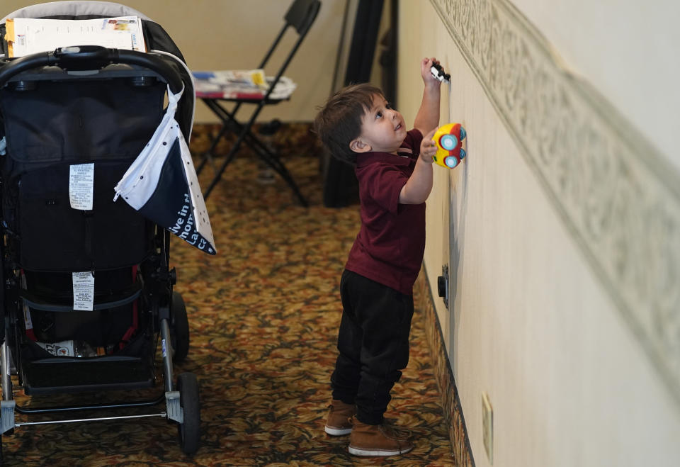 Two-year-old Rodrigo Guacapan runs his toy vehicles on the wall as his parents attend an orientation session for recent immigrants Monday, May 20, 2024, in Denver. (AP Photo/David Zalubowski)