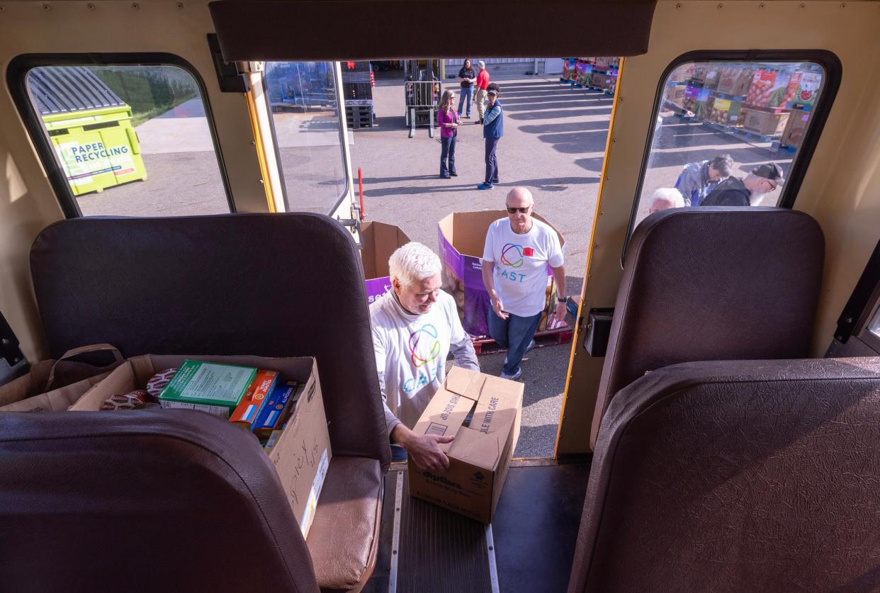 Mike Savage, left, and Jim Bellamy with Caring and Serving Together help unload a Canton Local school bus at the Akron-Canton Regional Foodbank's Stark County campus Tuesday in Canton. Volunteers helped unload food as part of the seventh annual "Hunger: The Bus Stops Here" fundraising drive.