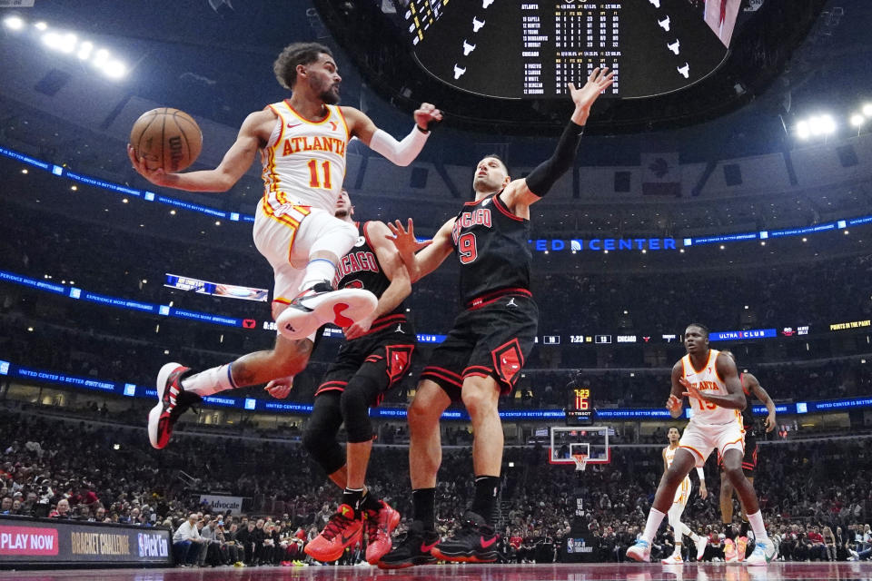 Atlanta Hawks guard Trae Young, left, looks to pass against Chicago Bulls guard Alex Caruso and center Nikola Vucevic, right, during the first half of an NBA basketball play-in tournament game in Chicago, Wednesday, April 17, 2024. (AP Photo/Nam Y. Huh)