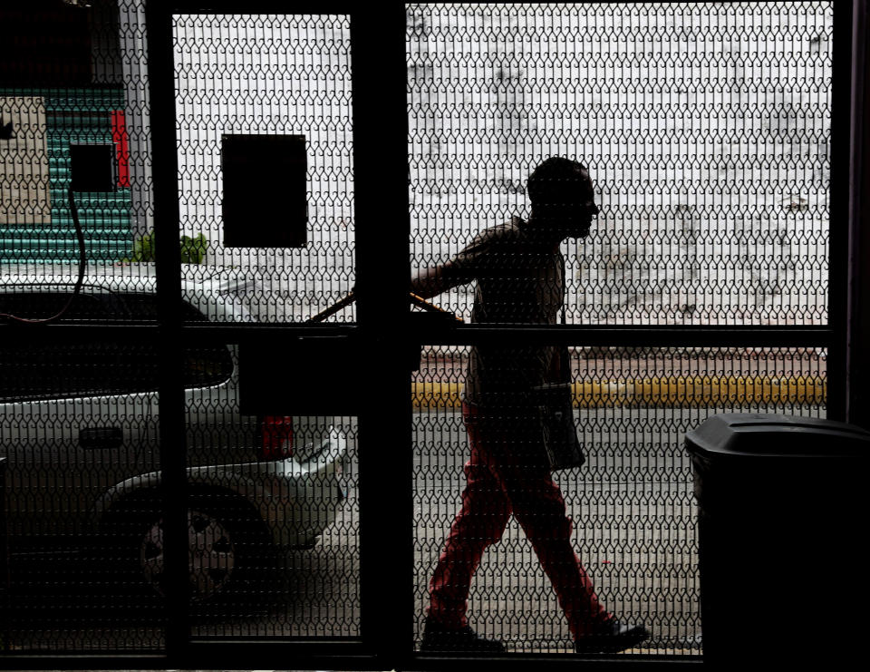 In this May 28, 2019 photo, a Cuban migrant that did not want to be identified is silhouetted as he walks by a gate in Tapachula, Chiapas state, Mexico. The 36-year-old man was one of the more than 600 migrants that broke out of the Siglo XXI migrant detention center in April. (AP Photo/Marco Ugarte)