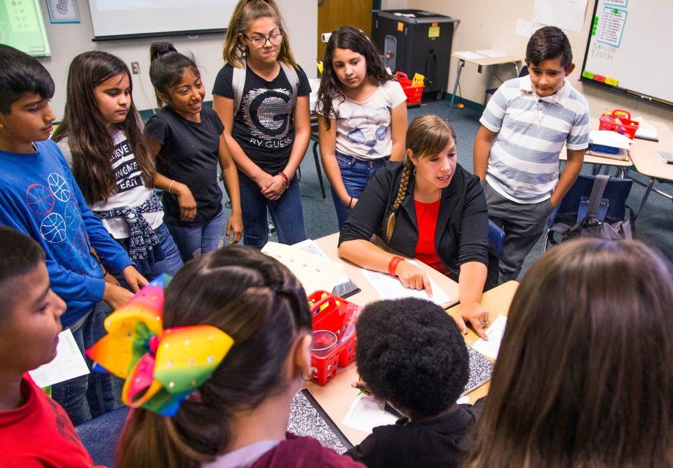 Rebecca Garelli , sitting, helps her 6th grade class at Sevilla West Elementary School in Phoenix.