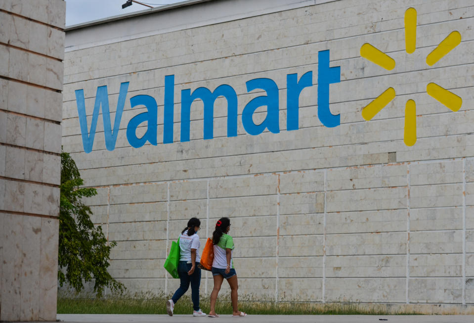 Two women walk towards a Walmart logo at the entrance to a Walmart store in Mexico.