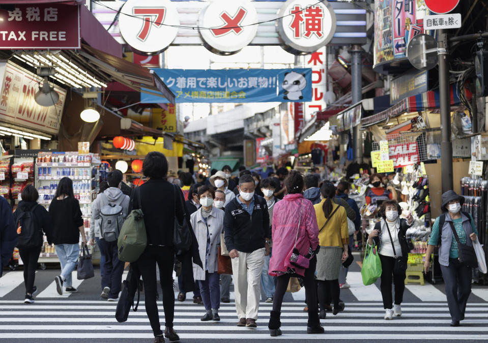 People wearing face masks walk across a traffic intersection in Tokyo on Thursday, Nov. 19, 2020. Japan's number of reported coronavirus infections hit a record high Thursday, and the prime minister urged maximum caution but stopped short of calling for restrictions on travel or business. (AP Photo/Hiro Komae)