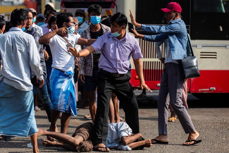 Military supporter points a sharp object as he confronts anti-coup protesters during a military support rally in Yangon