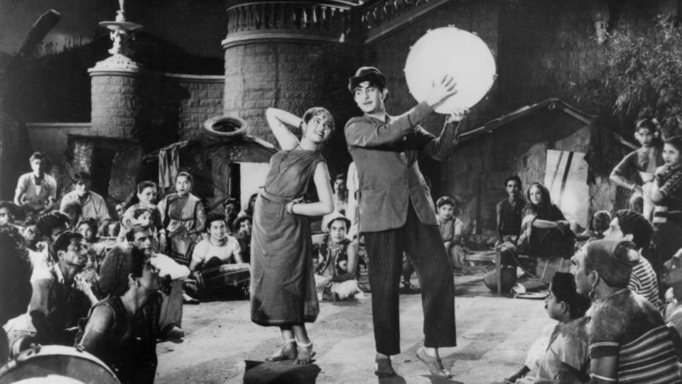 Nargis in a sari and Raj Kapoor in a suit are shown dancing.