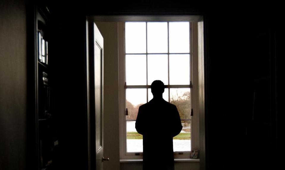 Man in overcoat standing looking out of window