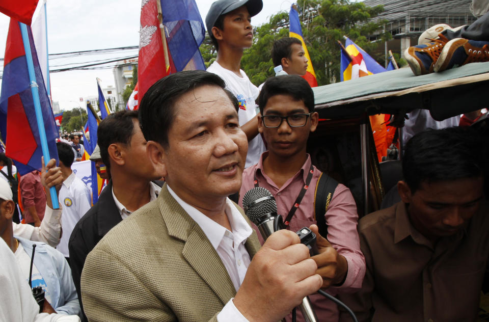 FILE - Thach Setha, foreground, a prominent vice president of the country's main opposition, Candlelight Party, talks to media members near the Vietnam Embassy in Phnom Penh, Cambodia, on July 21, 2014. The top Cambodian opposition politician who was sentenced last month to 18 months in prison for issuing worthless checks has been convicted and sentenced to three years additional imprisonment for incitement to commit a felony and incitement to discriminate on the basis of race, religion or nationality. (AP Photo/Heng Sinith, File)