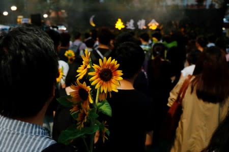 Pro-democracy activists hold sunflowers to attend a public memorial for anti-extradition bill protester Marco Leung, who died after falling from a scaffolding at the Pacific Place complex while protesting, in Hong Kong