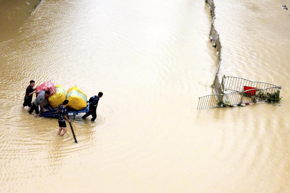 In this photo released by Xinhua News Agency, residents move their belongings across a flooded street in Zhengzhou in central China's Henan province on Wednesday, July 21, 2021. China's military has blasted a dam to release floodwaters threatening one of its most heavily populated provinces, as the death toll in widespread flooding rose to more than two dozens. (Zhu Xiang/Xinhua via AP)