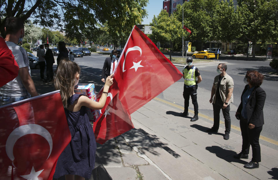 Security officers surround the members of a family as the car carrying Turkey's President Recep Tayyip Erdogan drives in a motorcade to the parliament to attend a ceremony in the capital Ankara, Turkey, Thursday, July 15, 2021. Turkey on Thursday marked the fifth anniversary of a failed coup attempt against the government, with a series of events commemorating victims who died trying to quash the uprising. (AP Photo/Burhan Ozbilici)