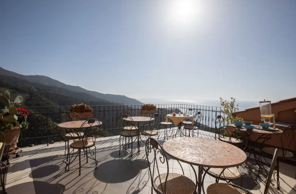 Outdoor terrace with breakfast tables overlooking the mountains and sea.