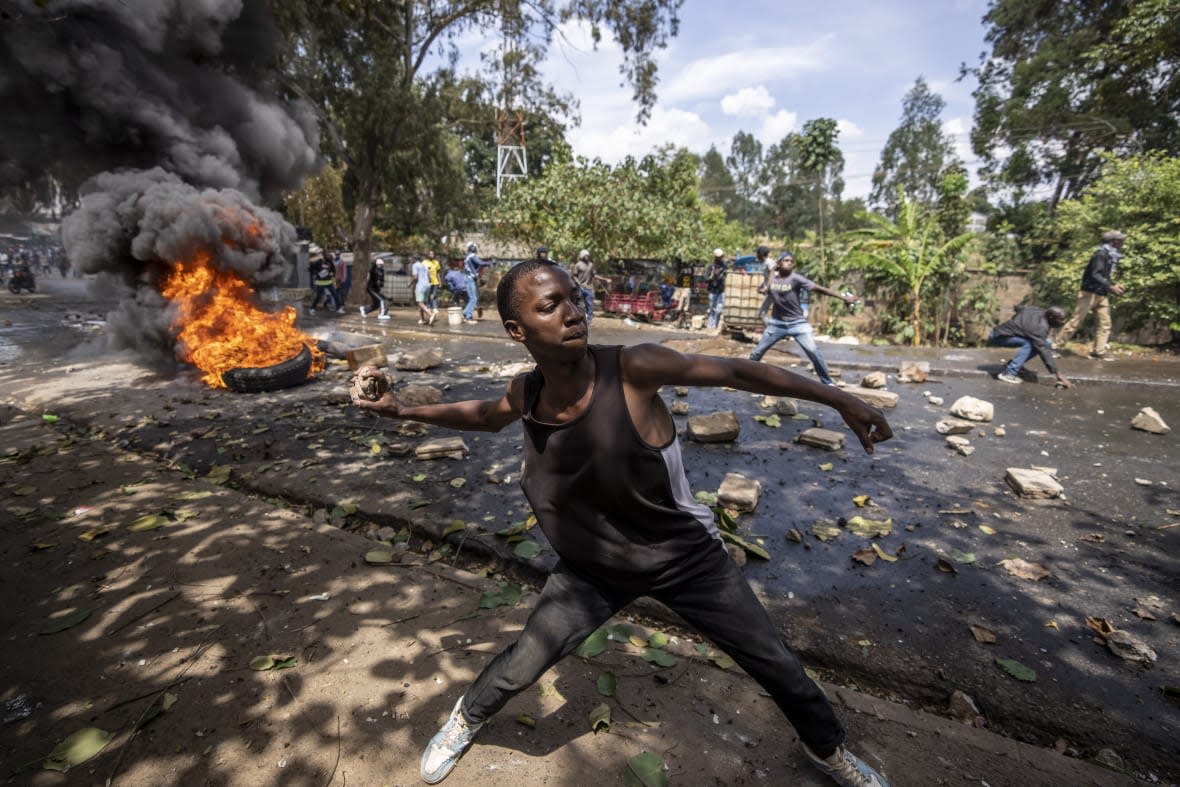 A protester throws rocks towards police in the Kibera slum of Nairobi, Kenya, Monday, March 20, 2023. (AP Photo/Ben Curtis)