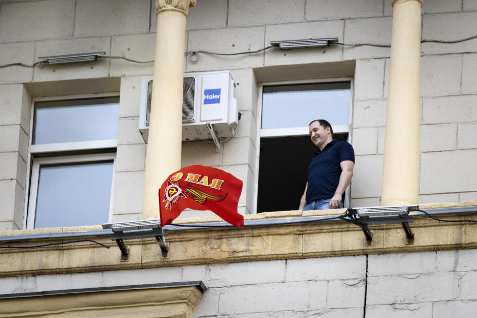 A man looks at a red flag with the words "May 9" which he just installed on his balcony during a minute of silence in memory of those killed during WWII as he stands on a balcony in Moscow, Russia, Saturday, May 9, 2020. Russian President Vladimir Putin has marked Victory Day, the anniversary of the defeat of Nazi Germany in World War II, in a ceremony shorn of its usual military parade and pomp by the coronavirus pandemic. (AP Photo/Alexander Zemlianichenko)