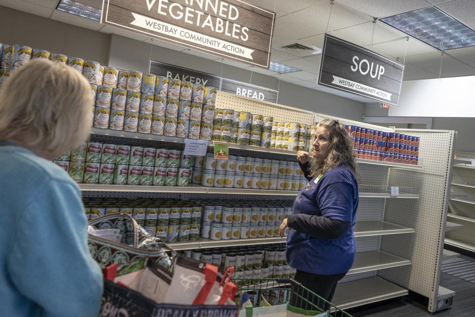 Volunteer Gail Simmons helps a client select groceries at Westbay Community Action’s Food Pantry. Westbay officials estimate its food pantry and home delivery services help approximately 20,000 people a year.