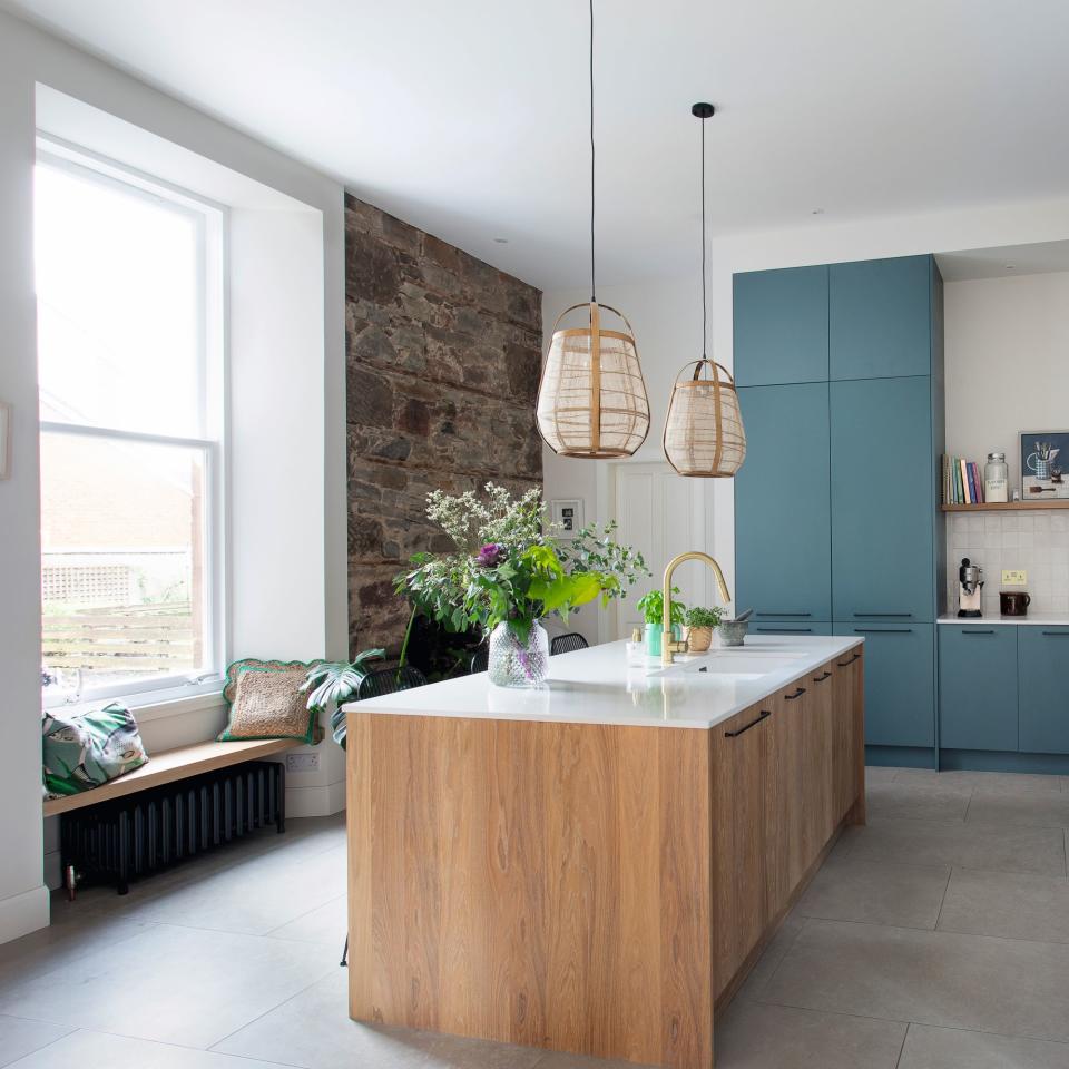 Wooden kitchen island with white top in a kitchen with blue cabinets