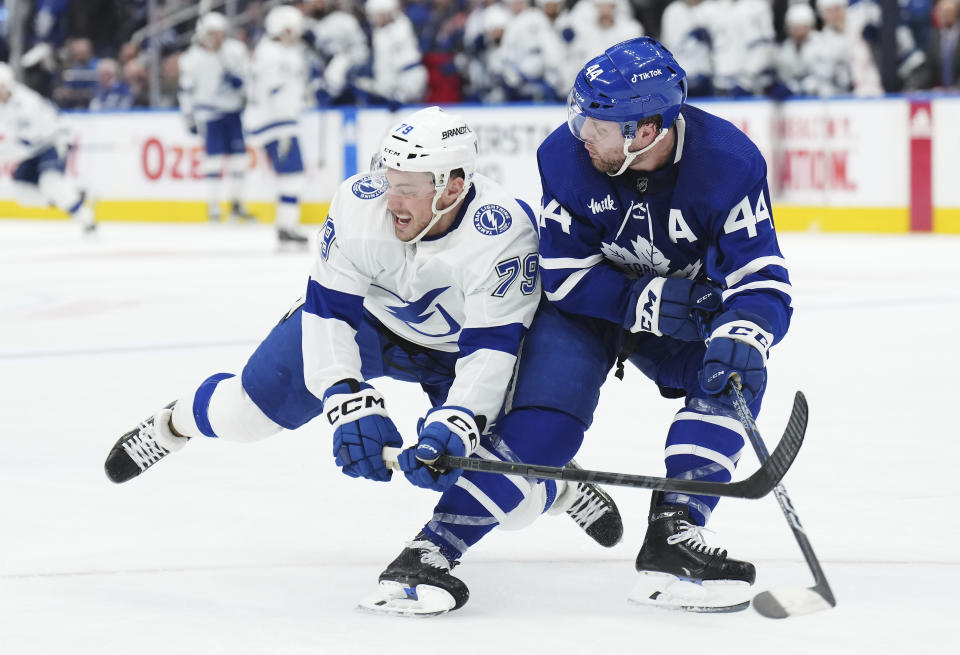 Tampa Bay Lightning forward Ross Colton (79) and Toronto Maple Leafs defenseman Morgan Rielly (44) watch the puck during the third period of Game 5 of an NHL hockey Stanley Cup playoffs first-round series Thursday, April 27, 2023, in Toronto. (Nathan Denette/The Canadian Press via AP)