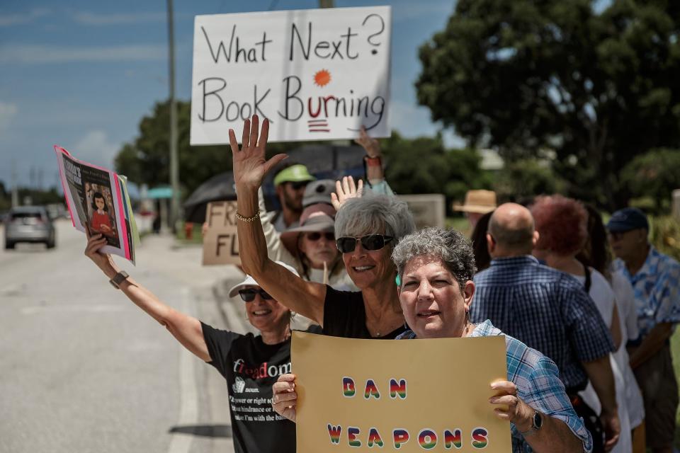 Sign-holders carrying messages in opposition to book bans stand along Forest Hill Boulevard outside of the The School District of Palm Beach County's Fulton-Holland Educational Services Center in Palm Springs on July 19, 2023.