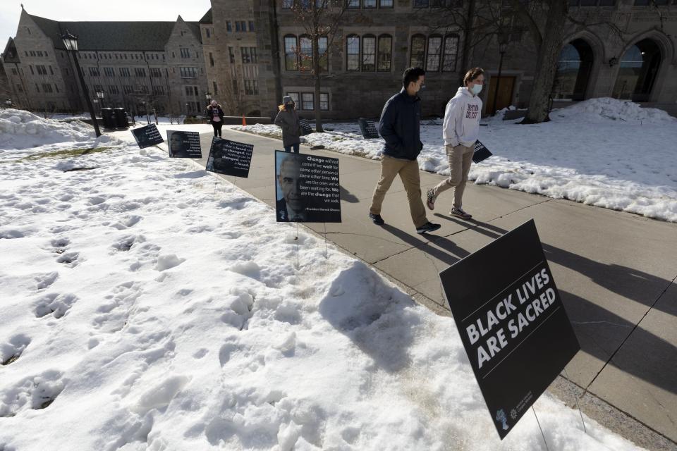 Students walk past Black History Month posters on the Boston College campus, Wednesday, Feb. 17, 2021, in Boston. Harassment by white male students targeting Black and Latina women housed in a Boston College dormitory has revived concerns about racism on campus. (AP Photo/Michael Dwyer)