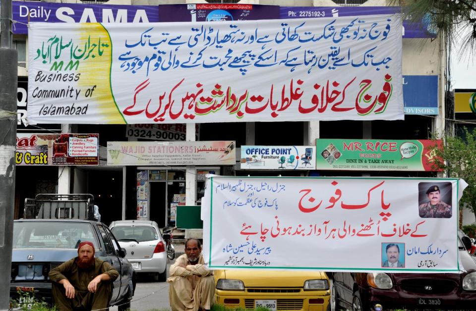 In this Friday, April 25, 2014 photo, banners supporting the army and its Inter-Services Intelligence wing are on display in the streets of Islamabad, Pakistan. The mystery signs arrived in Pakistan as its powerful military faces off with the country’s largest private television station over allegations that its forces were behind a shooting that seriously wounded Hamid Mir, one of its top anchors. But behind the chanting demonstrations and garish loyalty posters lies the deep challenge confronting Pakistan: Where does power lie in this country that’s undergone three military coups since independence, with its army or its nascent civilian government? Banners read, top, "anything negative against army is not acceptable, and bottom, "every voice rising against Pakistan army should be silent." (AP Photo/B.K. Bangash)