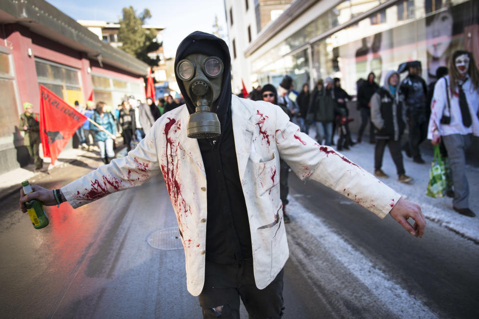A demonstrator walks in the street with a gas mask during a protest against the Davos World Economic Forum, WEF, on the side line of the 44. Annual Meeting of the World Economic Forum, WEF, in Davos, Switzerland, Saturday, Jan. 25, 2014. (AP Photo/Keystone,Jean-Christophe Bott)