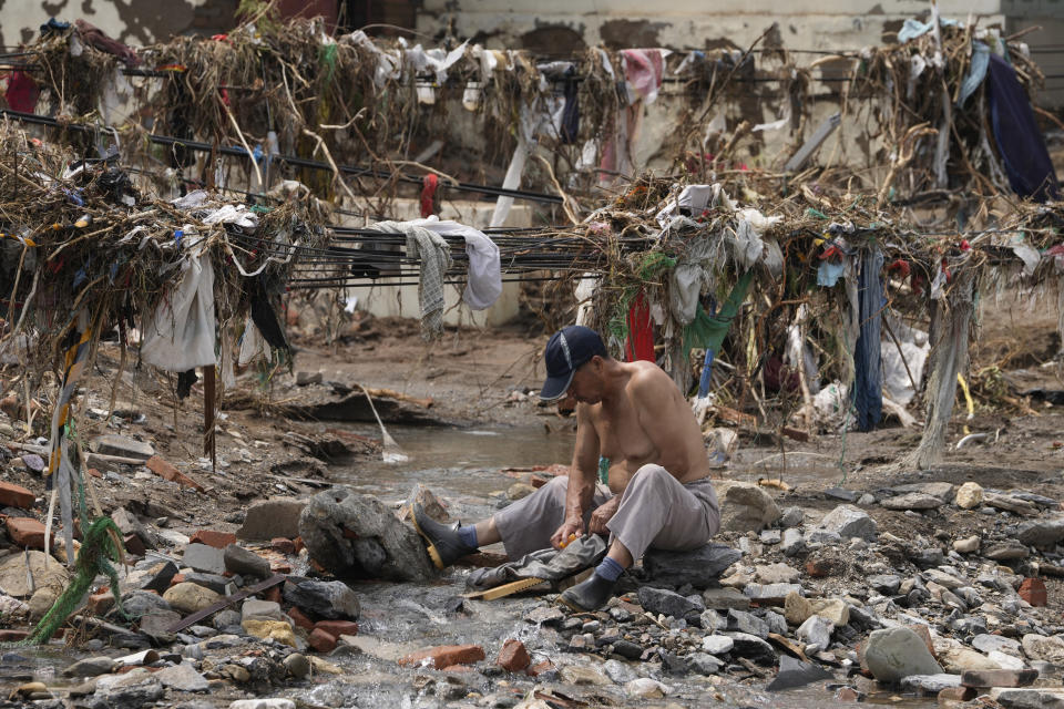 A man washes his clothes in a stream near debris left over after flood waters devastated the village of Nanxinfang on the outskirts of Beijing, Friday, Aug. 4, 2023. Heavy rain and high water levels on rivers in northeastern China were threatening cities downstream on Friday, prompting the evacuation of thousands, although the country appears to have averted the worst effects of the typhoon season battering parts of east Asia. (AP Photo/Ng Han Guan)