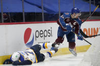 Colorado Avalanche left wing Gabriel Landeskog, right, picks up the puck as St. Louis Blues center Oskar Sundqvist loses his footing and slides against the boards during the second period of an NHL hockey game Wednesday, Jan. 13, 2021, in Denver. (AP Photo/David Zalubowski)