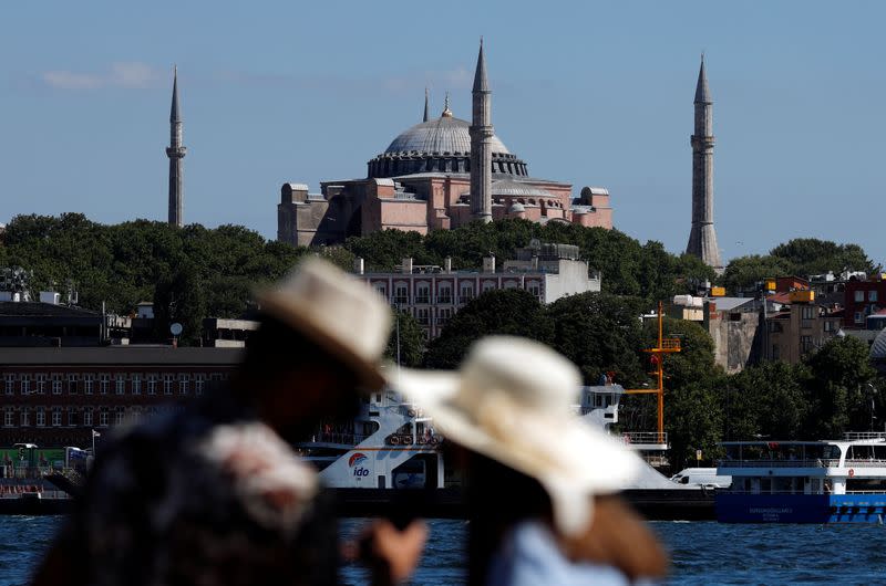 A couple stand by the Marmara Sea with the Hagia Sophia or Ayasofya-i Kebir Camii in the background in Istanbul