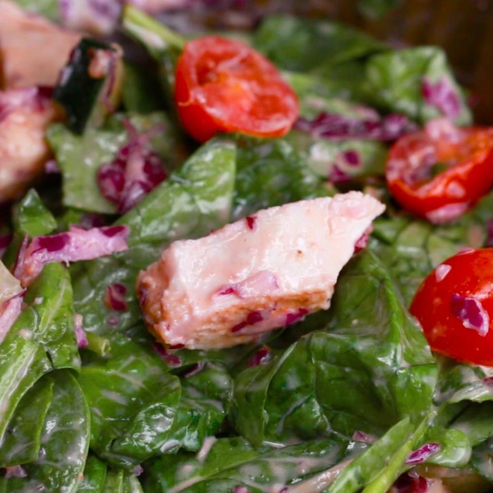 Greens topped with chicken, tomatoes, and a creamy dressing