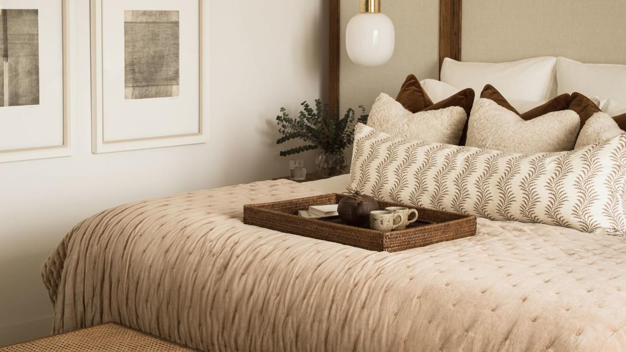  A soft. plush neutral bed with throw blanket and cushions 