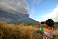 <p>A boy takes pictures during Mount Agung’s eruption seen from Kubu sub-district in Karangasem Regency on Indonesia’s resort island of Bali on Nov. 26, 2017. (Photo: Sonny Tumbelaka/AFP/Getty Images) </p>