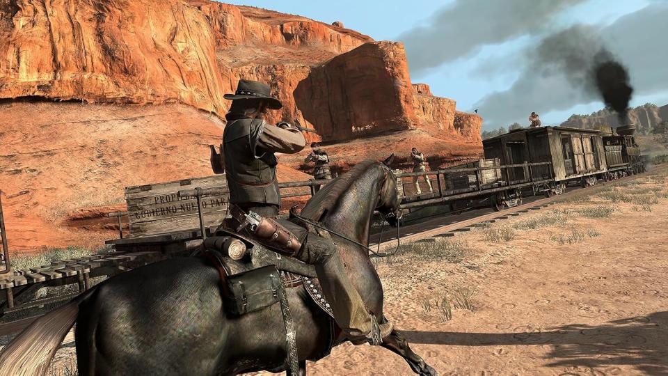 Gameplay-Screenshot von Red Dead Redemption, portiert auf die PS4.  John Marston (Protagonist) reitet auf einem Pferd und zielt mit einem Gewehr auf einen fahrenden Zug, während Gesetzlose auf ihn schießen.  Dunkler Rauch kommt aus der Lokomotive des Zuges, dahinter ist felsiges südwestliches Gelände zu erkennen.