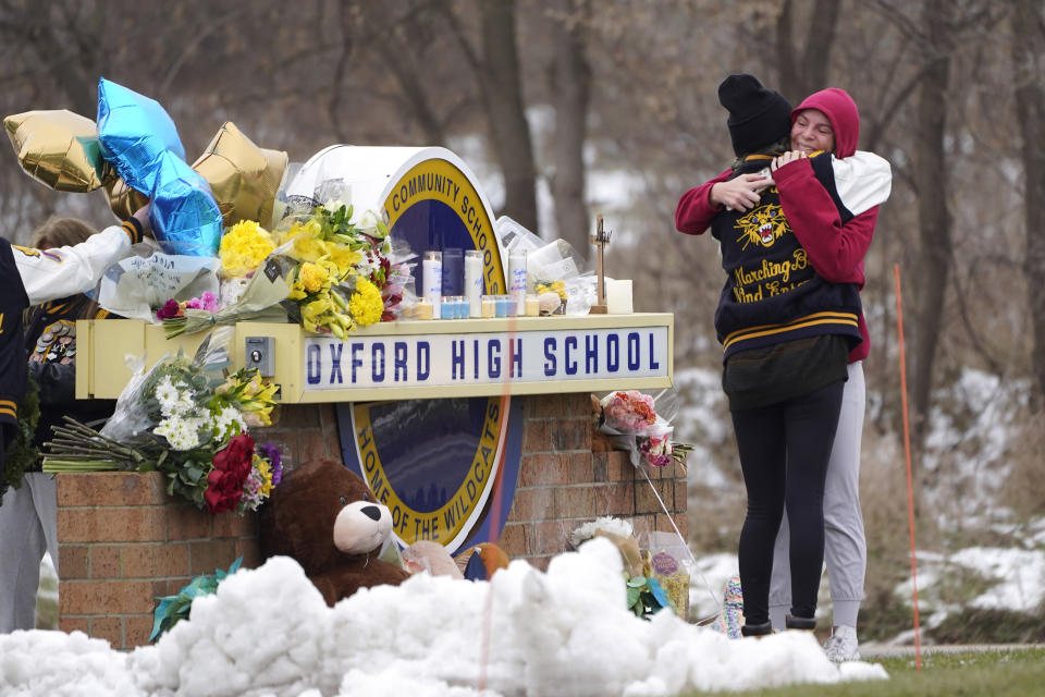 FILE - Students hug at a memorial at Oxford High School in Oxford, Mich., Dec. 1, 2021. Authorities say a 15-year-old sophomore opened fire at Oxford High School, killing four students and wounding seven other people Nov. 30, 2021. The May 2022 shooting rampage in a Buffalo supermarket, carried out by an 18-year-old who was flagged for making a threatening comment at his high school the year before, highlights concerns over whether schools are adequately supporting and screening students. (AP Photo/Paul Sancya, File)