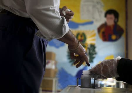 A polling center officer applies ink on a finger of a man after he voted in Caracas, June 28, 2015. REUTERS/Jorge Dan Lopez