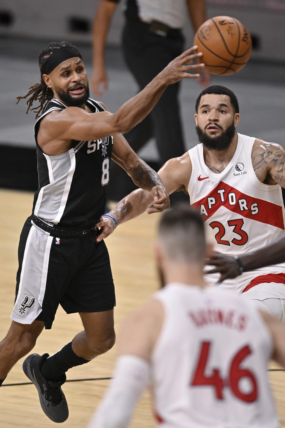 San Antonio Spurs' Patty Mills (8) passes as he drives against Toronto Raptors' Fred VanVleet (23) during the first half of an NBA basketball game Saturday, Dec. 26, 2020, in San Antonio. (AP Photo/Darren Abate)