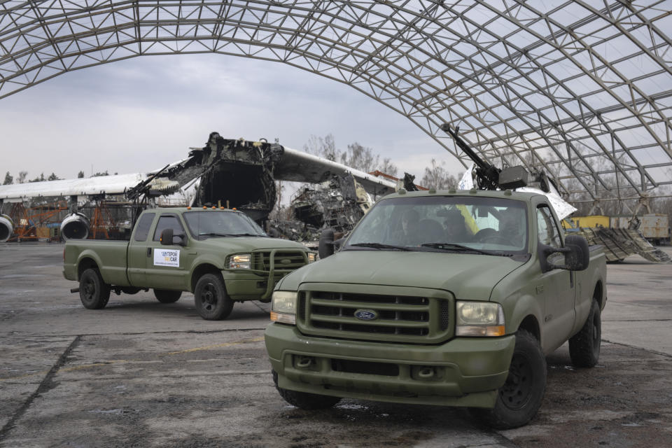 Crews of mobile air defence units are seen at the Antonov airport as the gutted remains of the Antonov An-225, the world's biggest cargo aircraft, destroyed during fighting between Russian and Ukrainian forces, is seen in the background, in Hostomel, on the outskirts of Kyiv, Ukraine, Saturday, April 1, 2023. (AP Photo/Efrem Lukatsky)