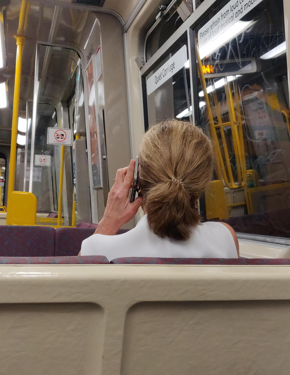 A woman using her mobile phone while sitting in a quiet train carriage. 