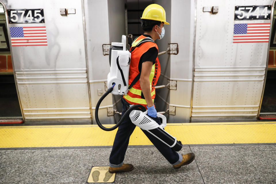 A contractor carries an electrostatic sprayer used to disinfect subway cars at the 96th Street station to control the spread of COVID-19, Thursday, July 2, 2020, in New York. Mass transit systems around the world have taken unprecedented — and expensive — steps to curb the spread of the coronavirus, including shutting down New York subways overnight and testing powerful ultraviolet lamps to disinfect seats, poles and floors. (AP Photo/John Minchillo)