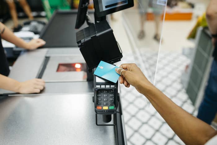 female human hand paying with a credit card on a cashier machine in a supermarket