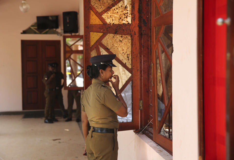 In this Thursday, April 25, 2019 photo, a Sri Lankan policewoman looks at the damage inside St. Sebastian's Church, one of the sites of Easter Sunday's bombings, in Negombo, north of Colombo, Sri Lanka. Nearly a week later, even after the cleaners have come through, the blood can still be seen clearly. The statues of Jesus and the saints are still speckled with fragments of shrapnel. The smell of death is everywhere, though the bodies are long gone. (AP Photo/Manish Swarup)