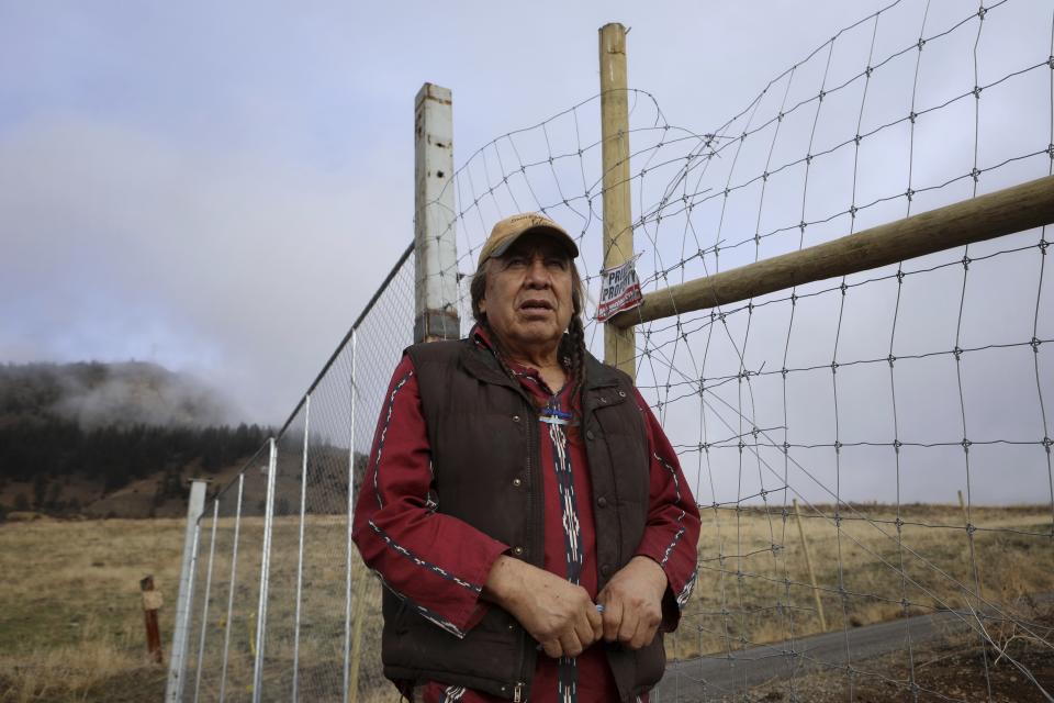 Dixon Terbasket, a syilx Okanagan wildlife technician with the Okanagan Nation Alliance from the Lower Similkameen Indian Band, stands outside of a fenced-off cherry orchard expansion site near Kelowna, British Columbia on Dec. 7, 2023. Terbasket and other conservation experts are concerned the cherry orchard's expansion is impacting the mobility of animals that use a nearby wildlife corridor in an area under threat from urban sprawl and other development. (Aaron Hemens/IndigiNews via AP)