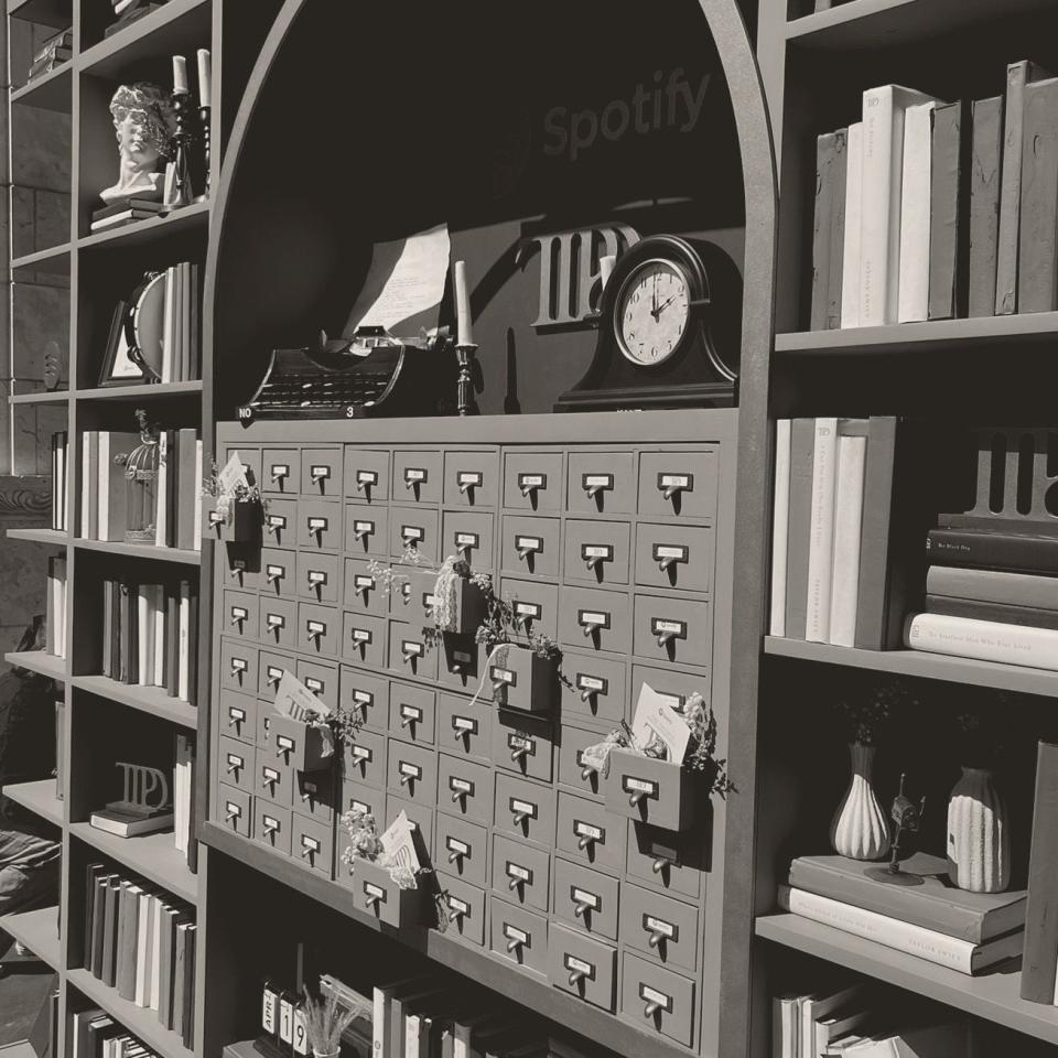 Library-style wall with numerous small drawers and assorted decorative items including books and a clock