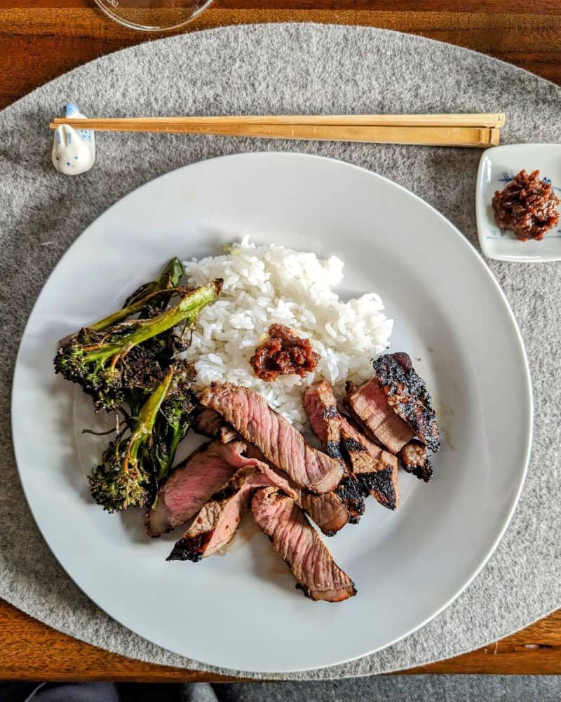 Steak, broccoli, rice on a plate with chop sticks