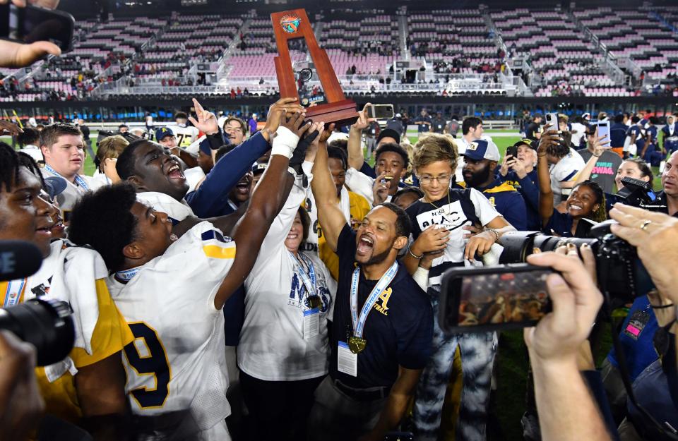 St. Thomas head coach Roger Harriott (center) and his team celebrate winning the the Class 7A state championship 42-14 over Tampa Bay Tech at DRV PNK Stadium, Fort Lauderdale, FL  Dec. 17, 2021. 