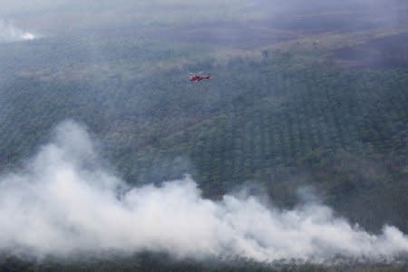 A helicopter carrying a water bucket is seen after dropping water on palm oil plantation in Ogan Komering Ilir, South Sumatra Province, Indonesia, July 18, 2018. Antara Foto/Nova Wahyudi/via REUTERS