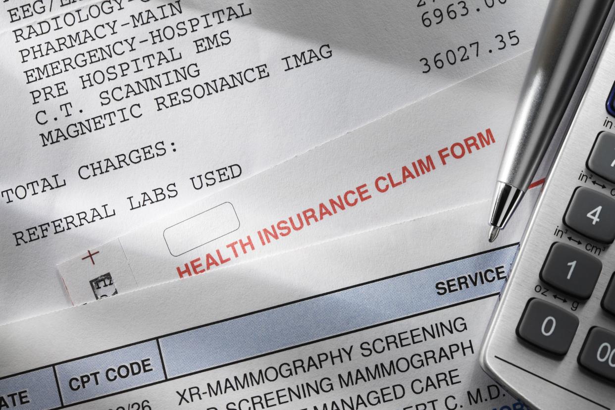 medical bills with insurance claim, calculator, and pen